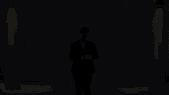 a man in a suit and tie is leaning against a pillar
