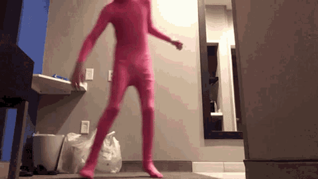 a person in a pink bodysuit is dancing in a hotel room .