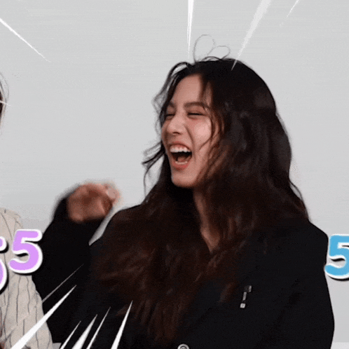 a woman in a black jacket is laughing with the number 5 in the background