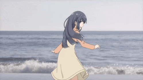 a girl in a dress is standing on the beach with her arms in the air