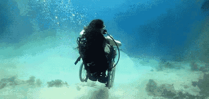 a scuba diver in a wheelchair is swimming underwater .