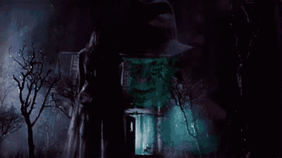a woman in a white dress is standing in front of a haunted house in the dark .
