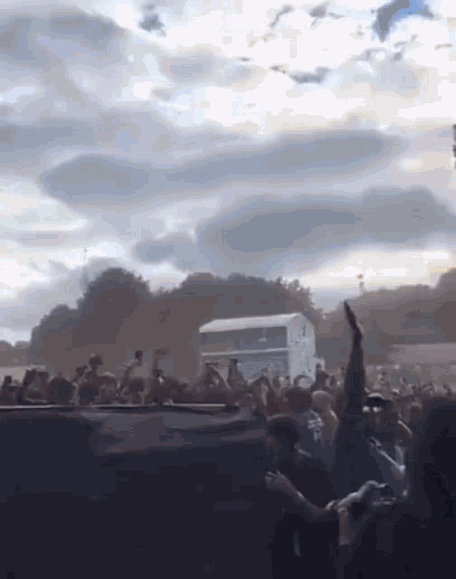 a crowd of people at a concert with a cloudy sky