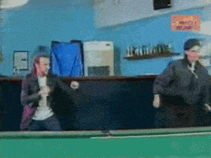 two men are dancing on a pool table in front of a sign that says ' a vehicle '
