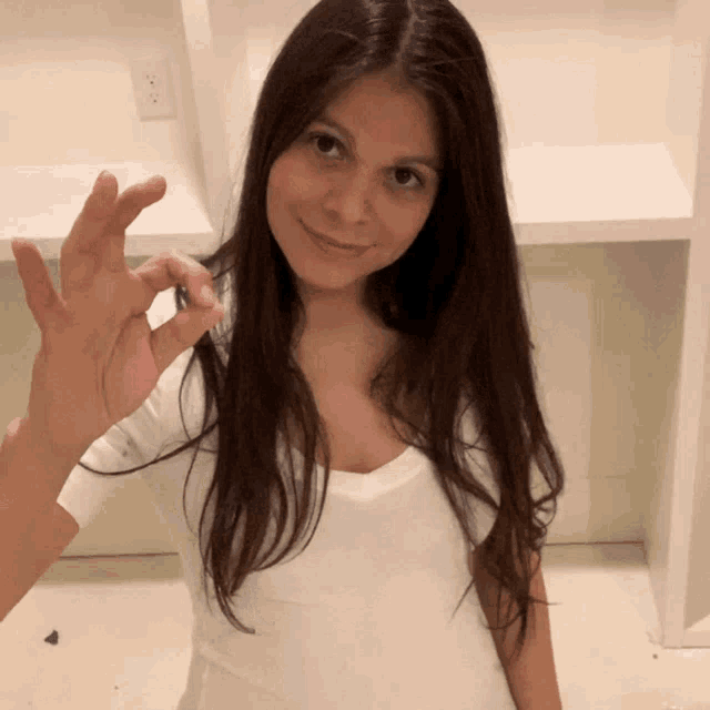 a woman in a white shirt is smiling and holding something in her hand