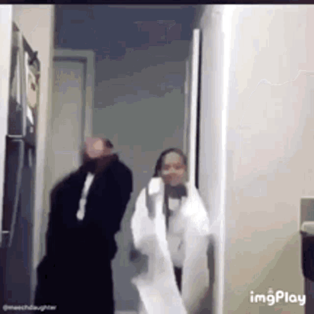 a man and a woman are standing next to each other in a hallway .