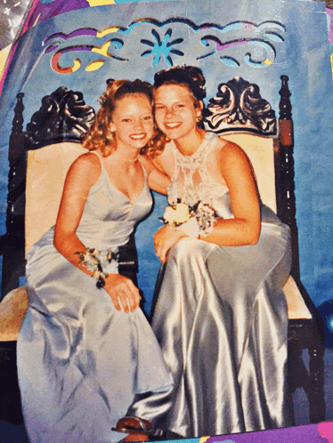 two women in prom dresses pose for a photo