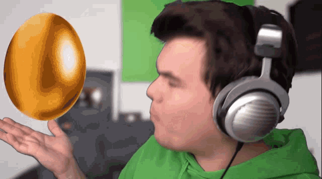 a man wearing headphones holds up a golden egg