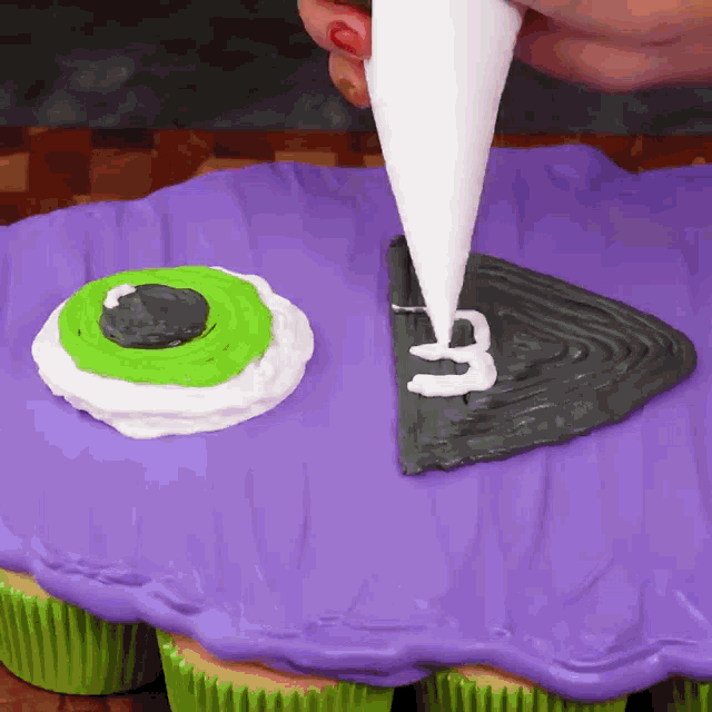 a person is frosting a purple cupcake with white frosting
