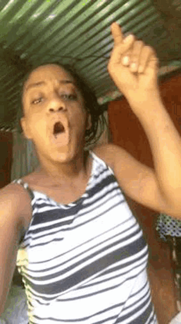 a woman in a striped tank top is making a funny face and giving the middle finger