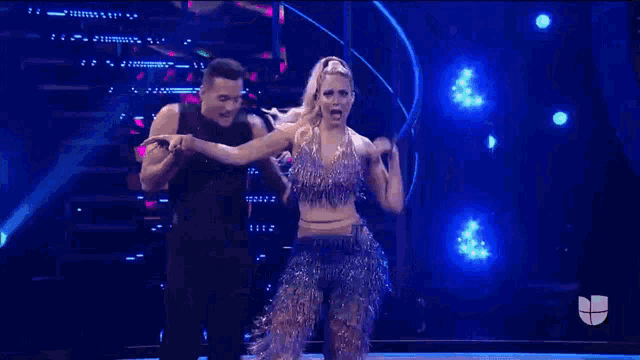 a man and a woman are dancing on a stage with blue lights .