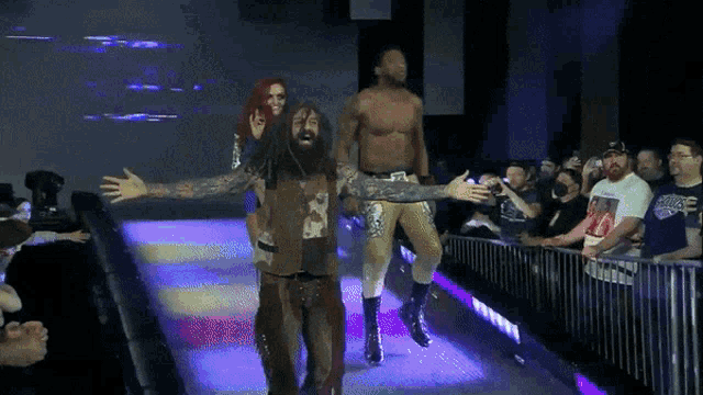 a wrestler with his arms outstretched walks down a ramp