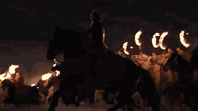 a group of people are dancing in front of a fire at night