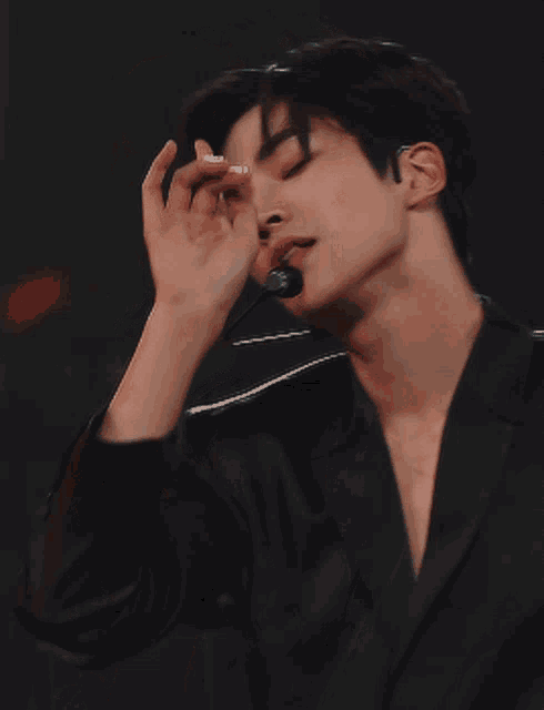 a young man wearing a black jacket and a microphone in his mouth