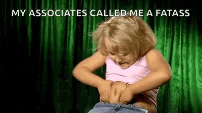 a little girl is holding her stomach in front of a green curtain and a green background .