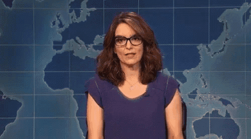 a woman wearing glasses is making a funny face in front of a map of the world