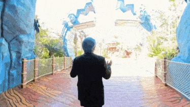 a man in a suit and hat is standing in front of a large blue archway
