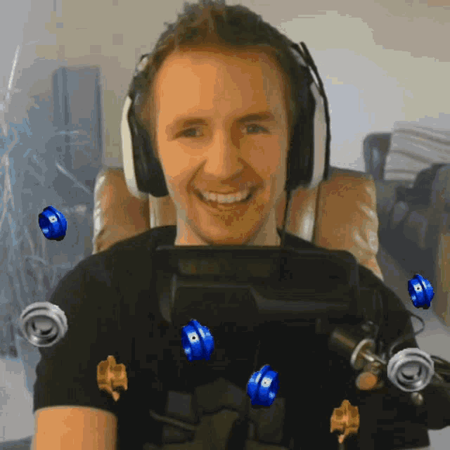 a man wearing headphones and a black shirt is smiling with blue balls around his neck