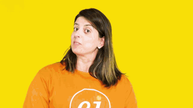 a woman wearing an orange shirt with the number 01 on it making a heart shape with her hands