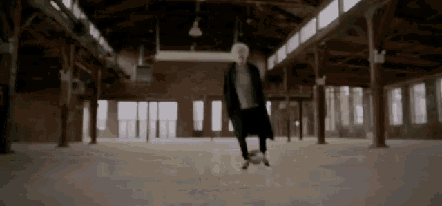 a man is kicking a soccer ball in an empty room .