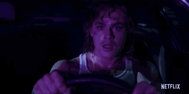 a man is driving a car at night with a netflix logo in the corner .