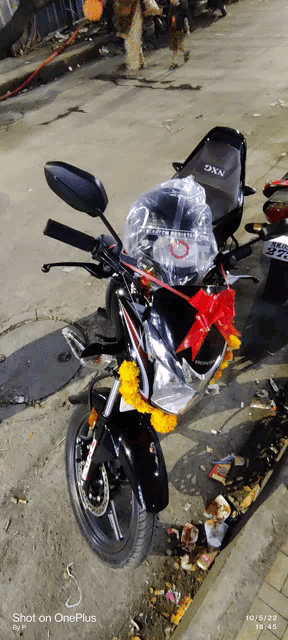 a black motorcycle is parked on the side of the road and has a bow on it