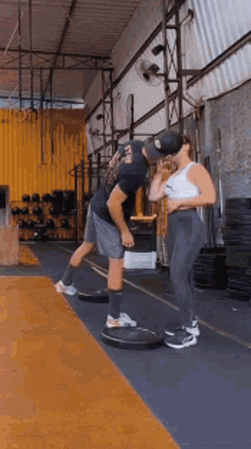 a man and a woman are kissing in a gym while doing exercises .