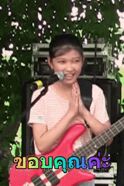 a young girl is playing a red guitar and singing into a microphone .