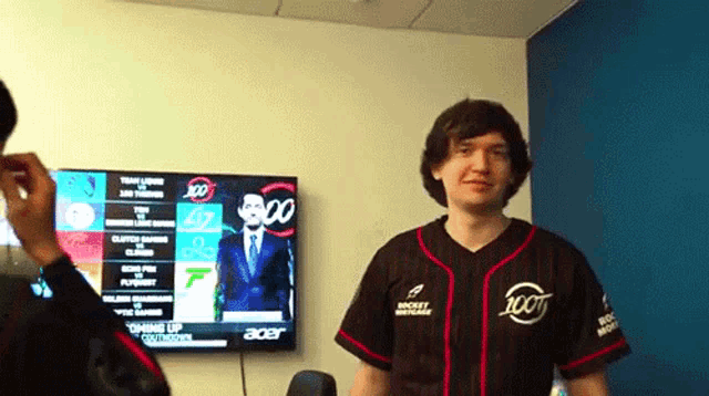 a man wearing a jersey that says rocket mortgage stands in front of an acer monitor