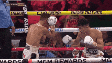 two boxers are fighting in a boxing ring with a banner that says energy that hits