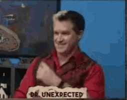 a man in a red shirt is sitting at a table with a sign that says dr. unexpected