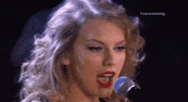 a close up of a woman singing into a microphone with her tongue out .