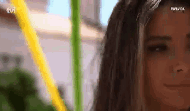 a close up of a woman 's face with a green pole in the background
