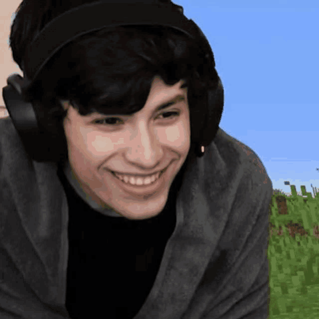 a young man wearing headphones and a black shirt is smiling .