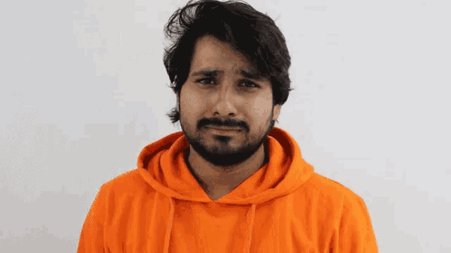 a man with a beard wearing a bright orange hoodie