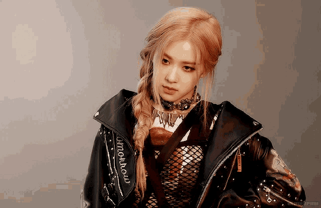 a woman wearing a black leather jacket and a braided ponytail looks at the camera .