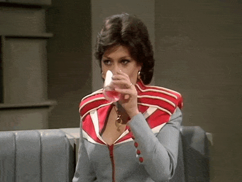 a woman in a red and white jacket is drinking from a cup