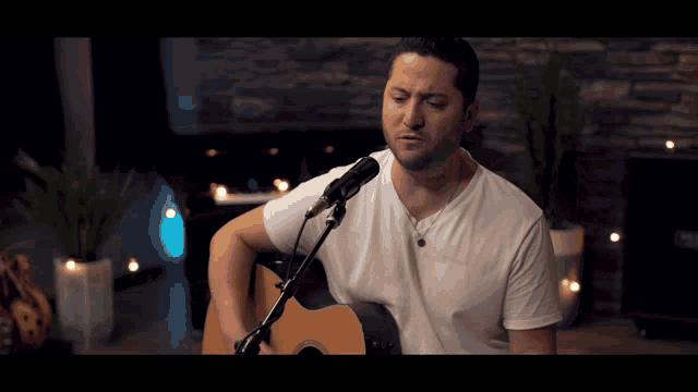 a man is singing into a microphone while playing a guitar