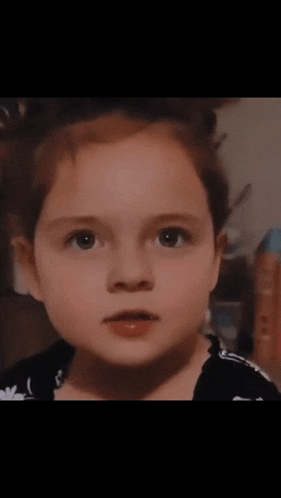 a close up of a little girl 's face with a surprised look on her face
