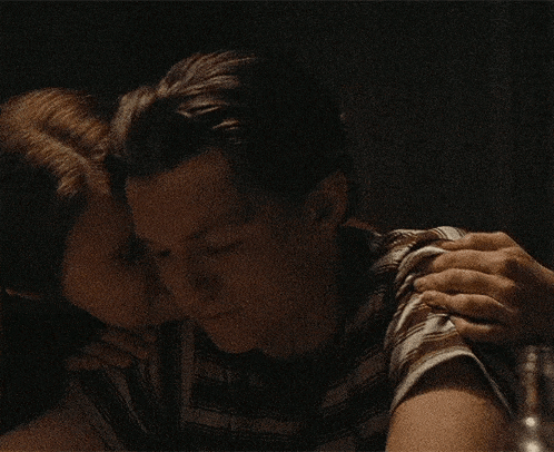 a man and a woman are hugging each other in a dark room and smiling .