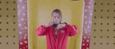 a man in a red jacket is standing in front of a yellow wall with polka dots .