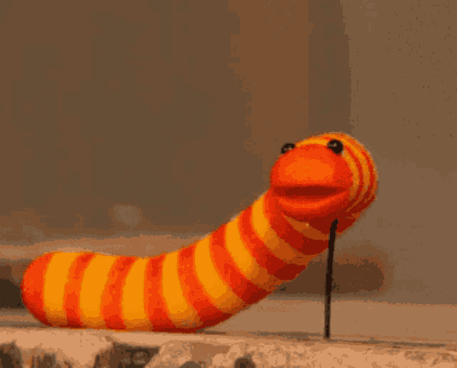 a stuffed orange and yellow worm with a long mouth