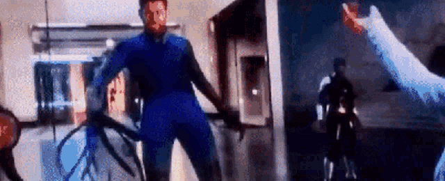 a man in a blue suit is holding a rope in his hand while standing in front of a building .