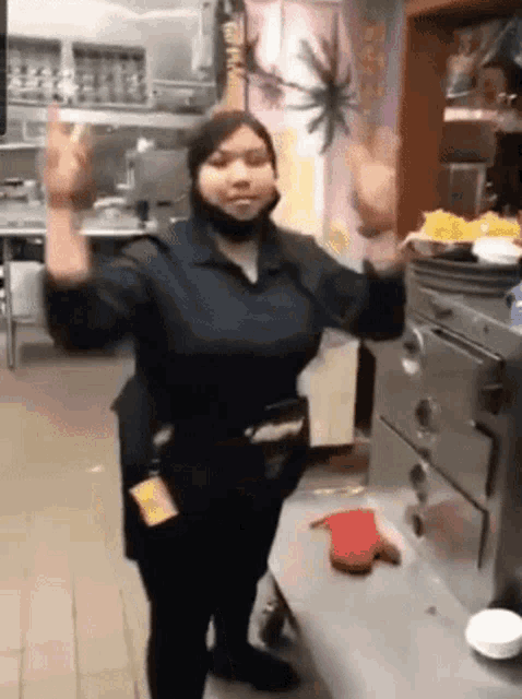 a woman wearing a mask is dancing in a restaurant kitchen