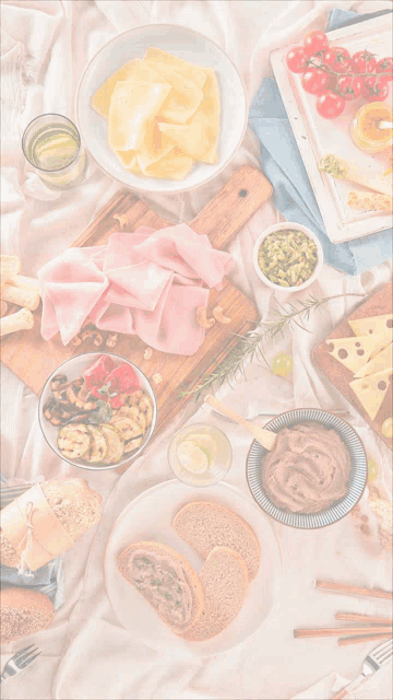 a table topped with a variety of food including ham cheese nuts and tomatoes
