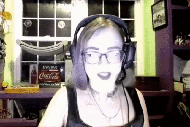 a woman wearing headphones stands in front of a sign that says drink coca-cola