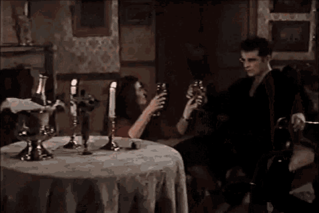 a man and woman are sitting at a table with candles