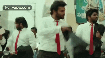 a group of men in suits and ties are dancing together .
