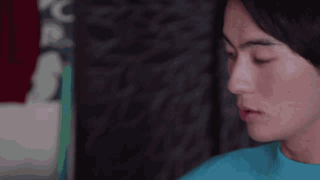 a close up of a woman 's face with a blue shirt on