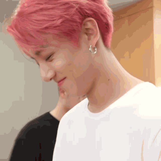 a close up of a person 's face with pink hair and earrings